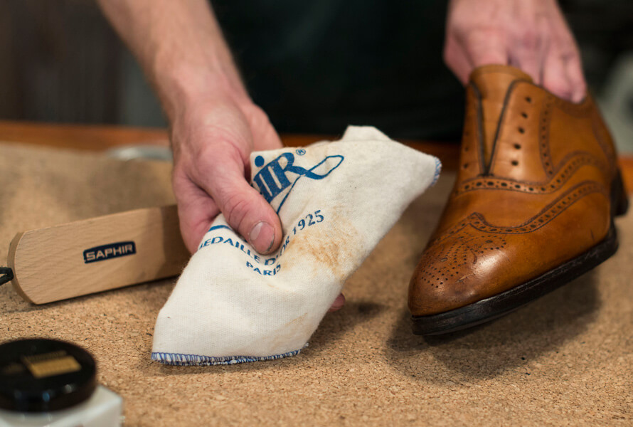 Torkar av gammal smuts från sko med läderrengöring